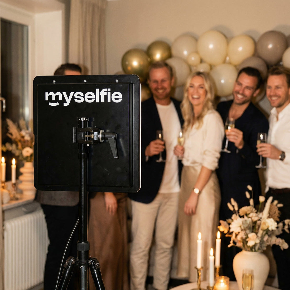 Gæster med champagne foran Myselfie photo booth og guldballoner til en fødselsdagsfest