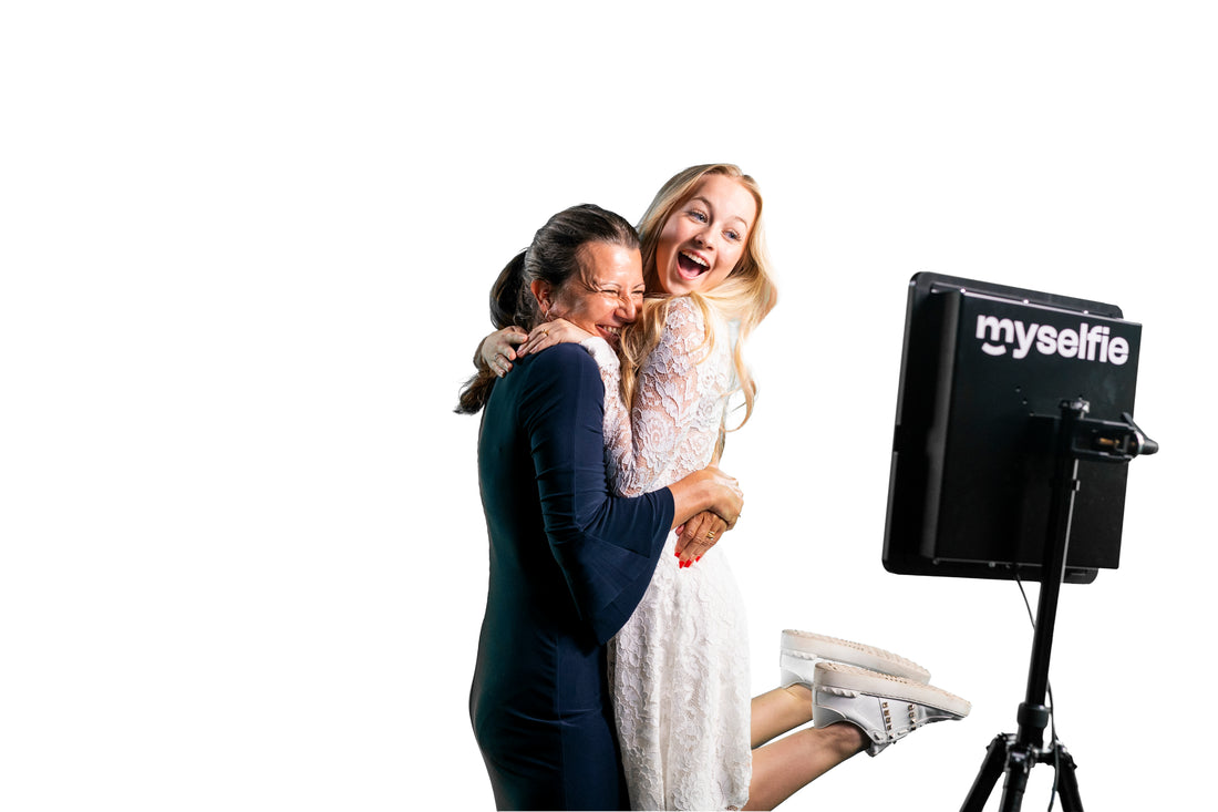 Konfirmand og hendes mor griner og krammer foran Myselfie photo booth