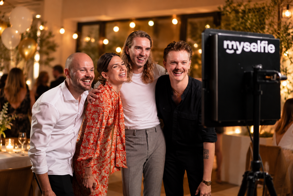 Familie og venner krammer og griner foran Myselfie photo booth til fest